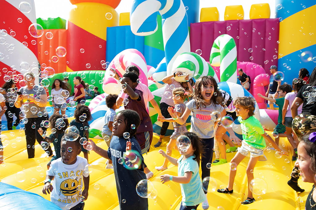 Happy kids playing on colorful candy cane themed inflatable bounce castle with bubble, outdoor commercial inflatable playground for birthday party and carnival rental