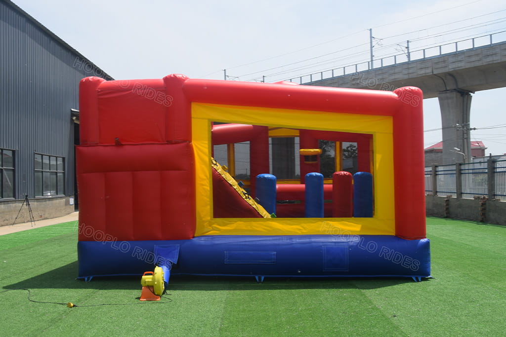 Red yellow blue commercial inflatable bounce house combo front view with obstacle pillars and built-in basketball hoop, outdoor jumping castle for party rental