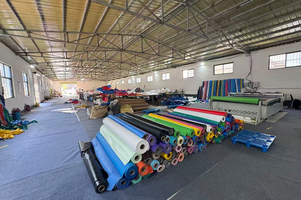 Inside Hooplo's inflatable manufacturing workshop in China, showing PVC material storage, cutting equipment, and professional production facilities.