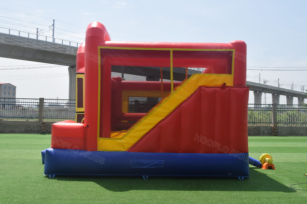 Back side view of commercial inflatable bounce house combo with large slide, matching electric air blower included for outdoor use