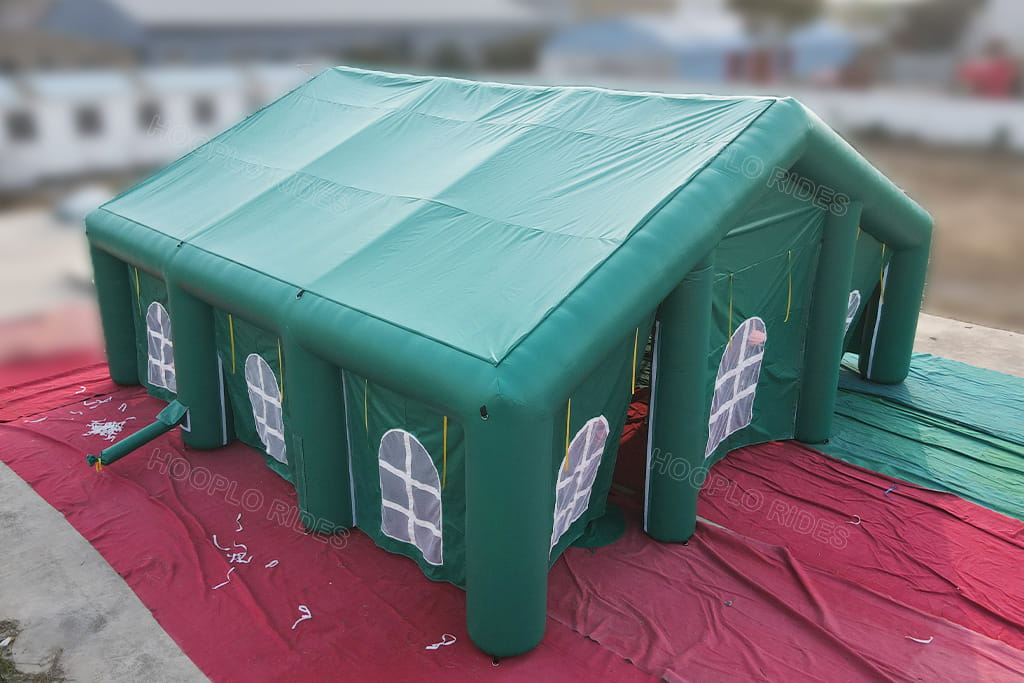Side full view of big green inflatable shelter with multiple arched mesh windows, durable inflatable house tent for party, workshop and outdoor rental business