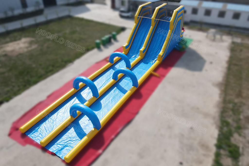Dual‑lane commercial inflatable water slide, view of sliding run‑out area with blue arch obstacles, giant inflatable racing slide for summer water amusement events