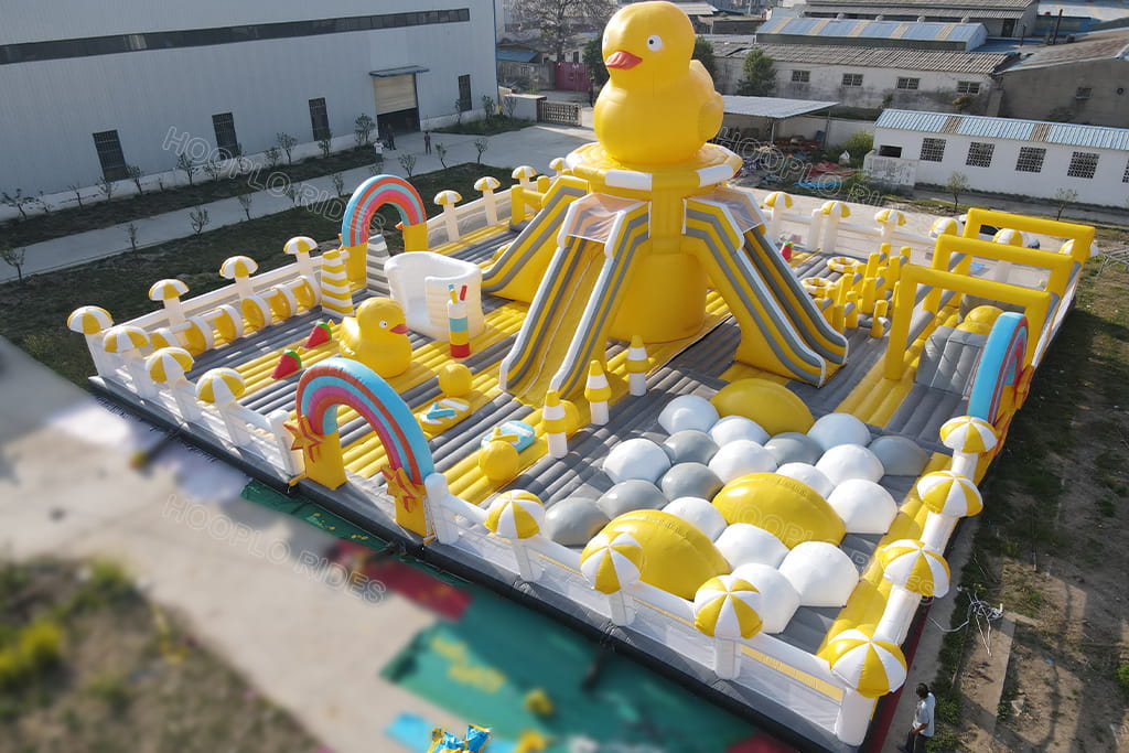 Commercial grade PVC giant rubber duck inflatable bounce park, overview of multi‑functional obstacle zone with slides, small duck decorations and ball pit area